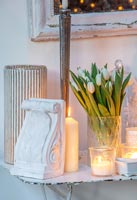 Decorative plaster with vase of white tulips and candles on vintage table 