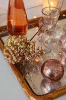 Bronze and gold decorations on tray with glasses and dried hydrangea flower