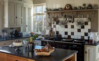 Country kitchen with tiled wall above Aga range cooker 