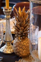 Gold sprayed pineapple and silverware on classic dining table 