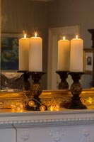 Candles and string of lights on mantelpiece with mirror 