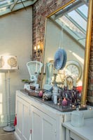 Sideboard with vintage ornaments and mirror in conservatory 