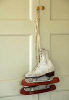 Vintage ice skates hanging from cupboard door