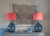 Apricot lamps on side table by painting of blossom 