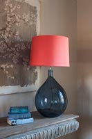 Blue glass lamp with apricot pink lampshade on stone table 
