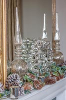 Silver glass wreath and garland of pine cones on mantelpiece 