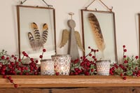 Christmas decorations and framed feathers on wooden shelf 