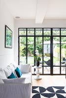 Modern living room with black framed windows and view to garden 