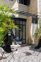 Curtains on pergola to create shade on gravel terrace 