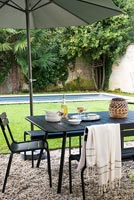 Outdoor dining area, lawn and swimming pool in walled garden 