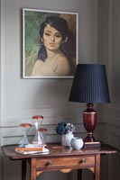 Vintage painting above wooden side table with lamp