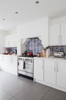 Modern white kitchen with patterned blue tiles 