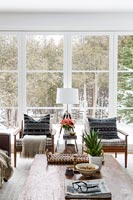 Wooden armchairs by large windows in winter