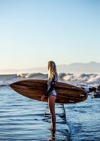 Young woman standing in sea holding a surfboard 