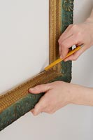 Using a pencil to mark shape of picture frame onto wall 