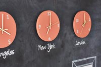 Orange wall clocks displaying different time zones on blackboard wall 
