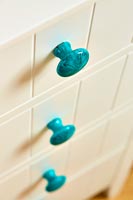 Turquoise door knobs on chest of drawers 