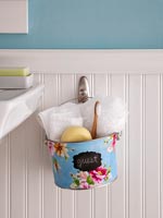 Colourful metal bucket suspended by sink to hold bathroom accessories