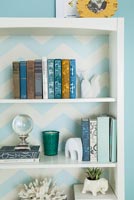 Bookshelf backed by striped wallpaper 