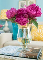 Bright pink flowers in glass vase on coffee table 