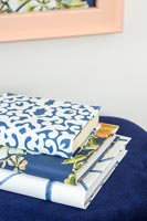 Books covered in patterned wallpaper on velvet seat