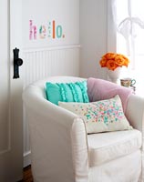 Upholstered armchair with colourful cut out fabric word on wall 