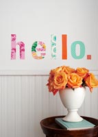 Orange flowers in a case with fabric cut out word on wall behind 