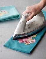 Pressing a cut out floral fabric onto another larger piece 