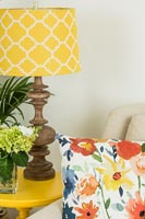 Colourful floral cushion and yellow patterned lampshade 