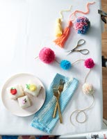 Table with cakes and decorative pom poms 