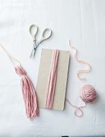 Pale pink thread on card and accessories for creating tassels 