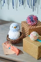 Bird made from pom poms in basket and gift decorations  