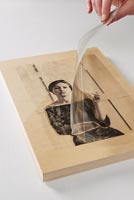 Peeling plastic from transferred picture pressed on to wooden block