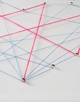 Blue and pink thread woven between drawing pins to create patterned frame 