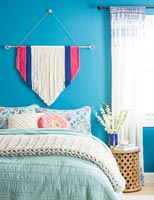 Fabric wall hanging on blue painted wall in modern bedroom