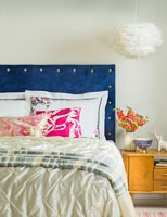 Blue velvet studded headboard in modern bedroom 