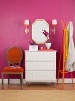 White chest of drawers next to pink painted wall in modern bedroom 