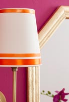 Detail of orange and white lampshade next to mirror 