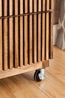 Detail of wooden slatted chest of drawers on castors 