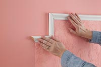 Sticking frame around section of pink embossed wallpaper 