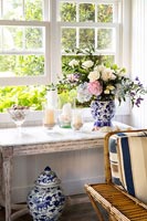 Vintage table with flower arrangement in blue and white ceramic vase 