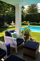 Luxury swimming pool in formal gardens with shaded seating area 