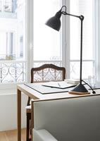 Lamp on desk by large windows 