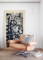 Leather armchair and artwork in corner of modern living room 
