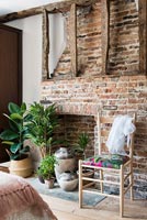 Brick fireplace with exposed beams and houseplants on hearth 