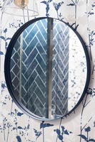 Herringbone tiling viewed through wall mounted bathroom mirror 
