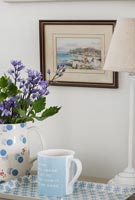 Jug of flowers and tray with tea on bedside table 