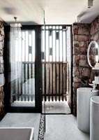 Modern bathroom with exposed stone wall 