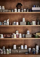 Large collection of thimbles and boxes displayed on wooden shelf unit 
