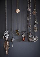 Collection of necklaces hanging on grey painted wall 